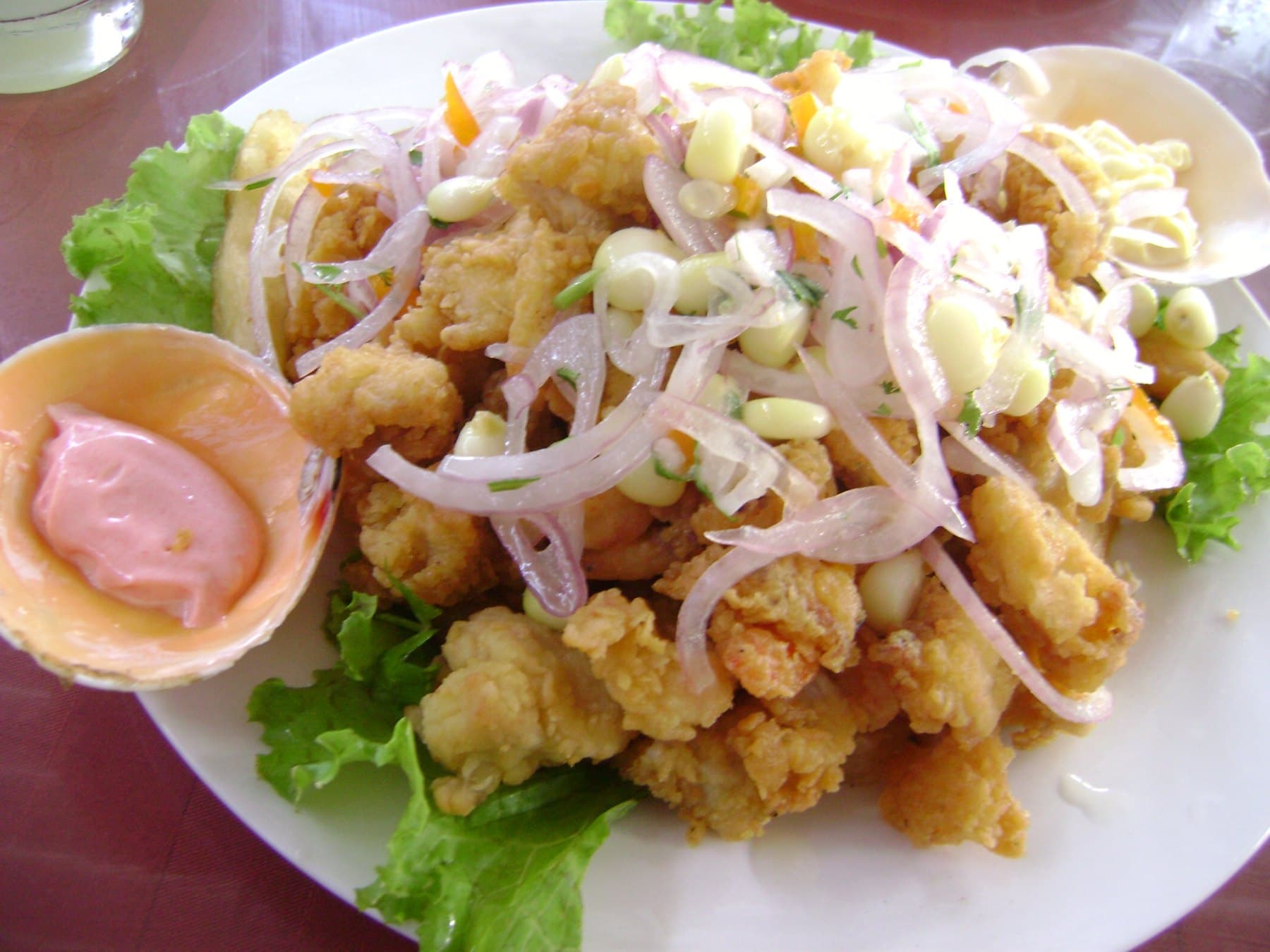 Chicharrón servido con sarsa criolla, choclo y lechuga fresca