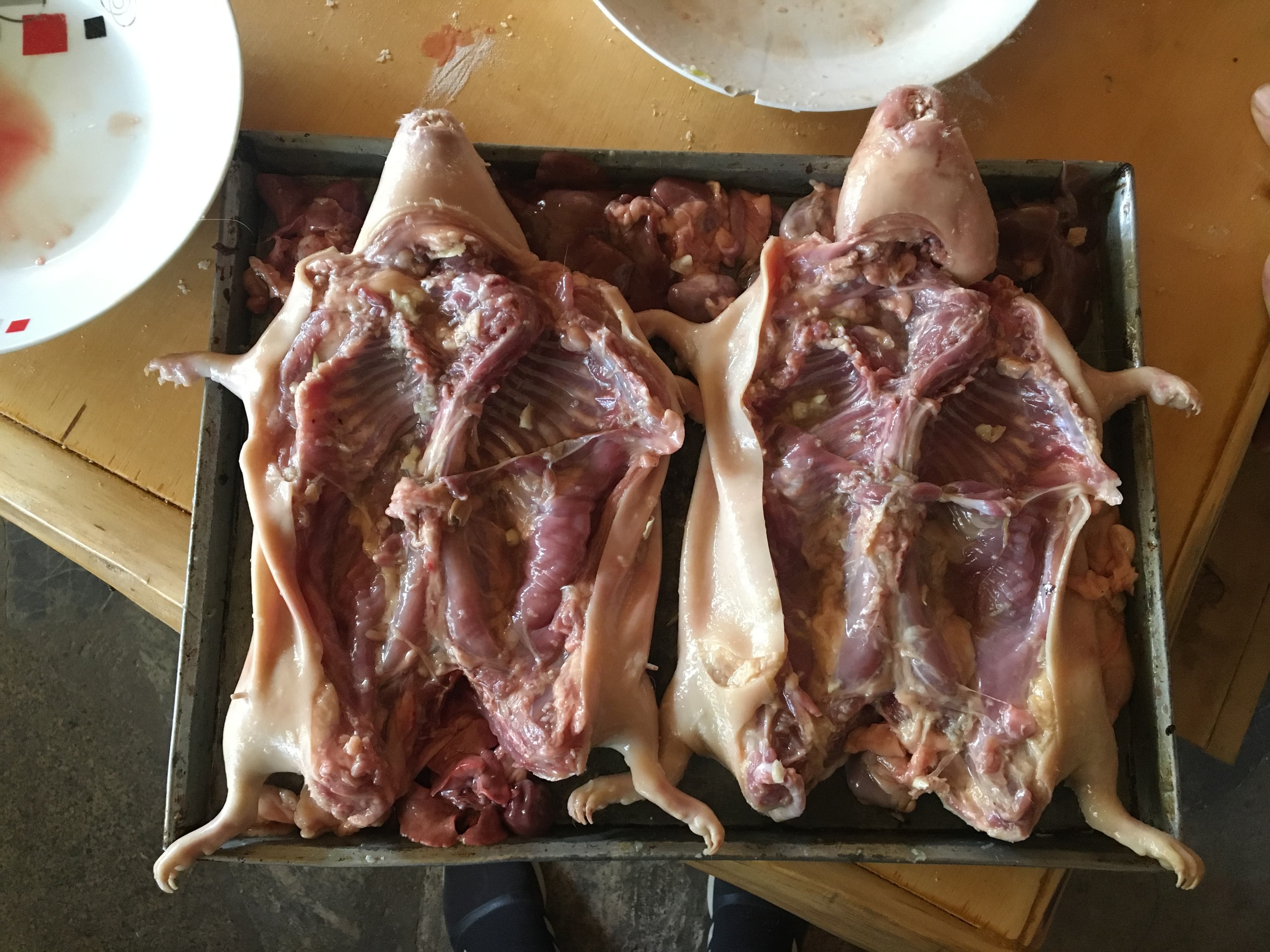 Cuyes crudos abiertos en bandeja, listos para el adobo