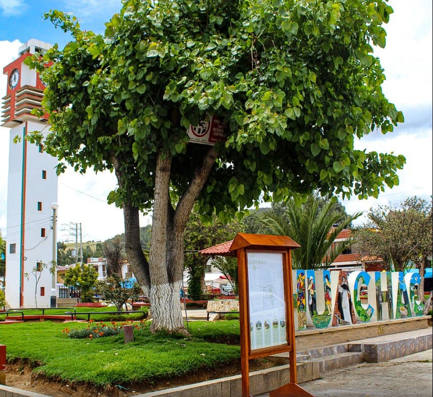 Plaza de Huáchac: árbol añoso y letrero del pueblo